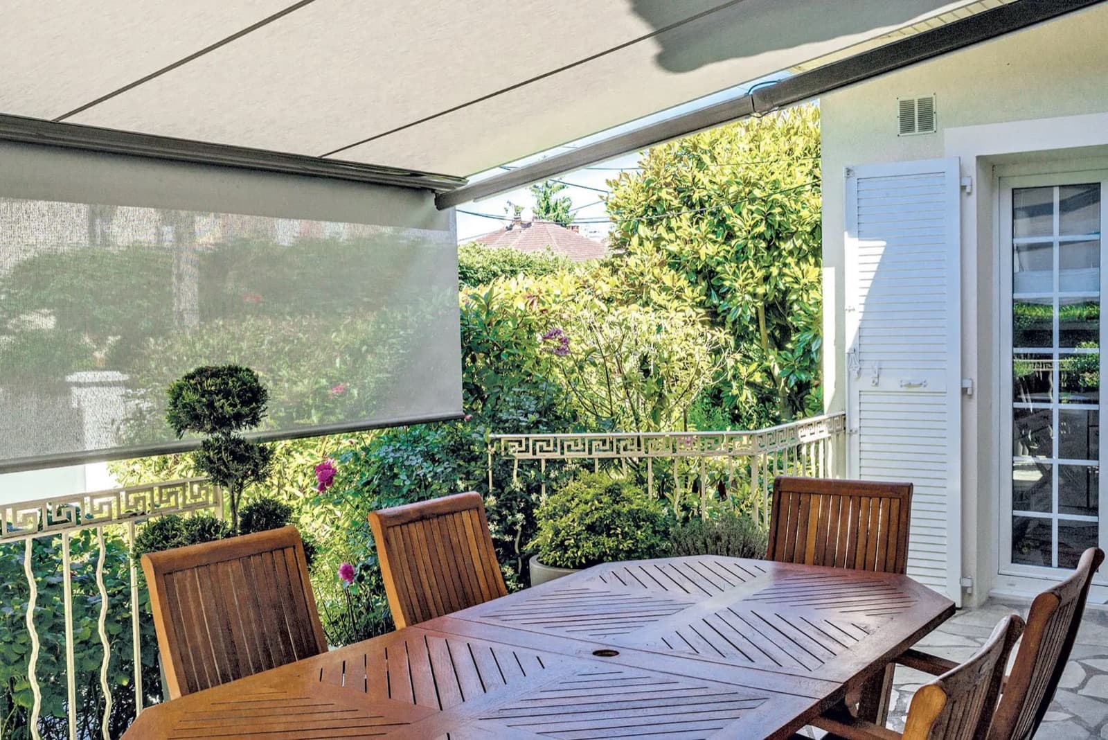 Balcon d'appartement ombragé par un store banne, table et chaises installées